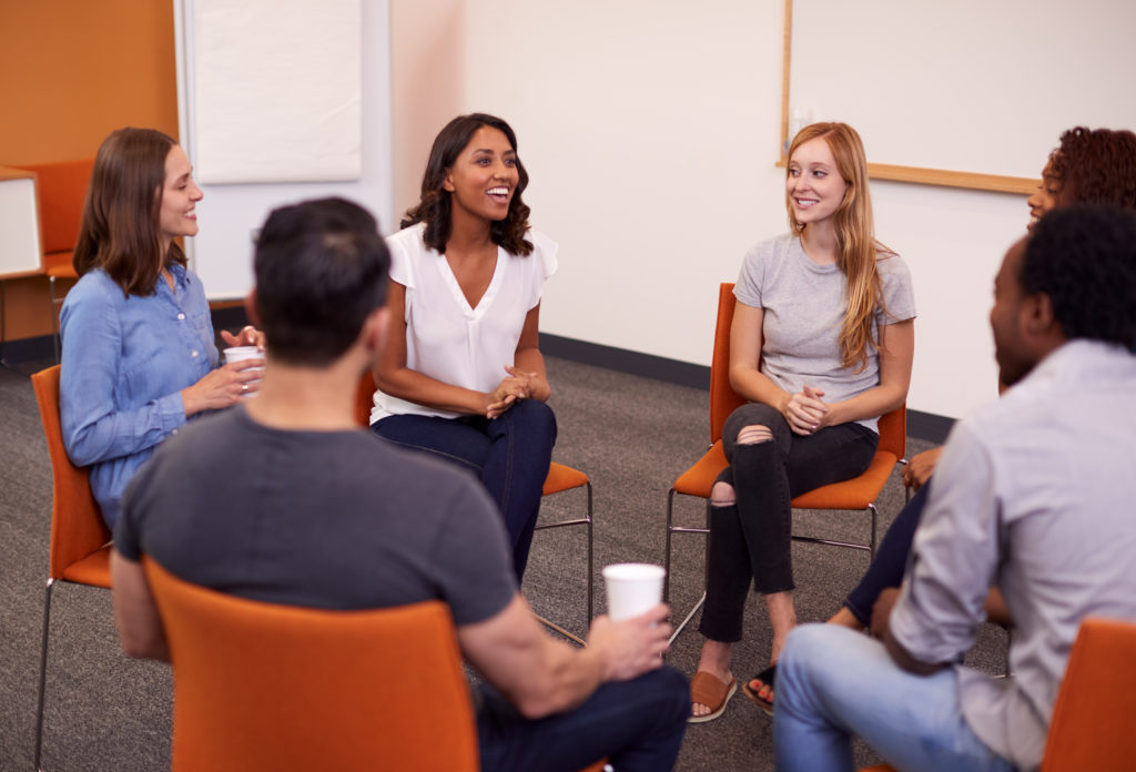 Multi-Cultural Group Of Men And Women At Mental Health Group Therapy Meeting