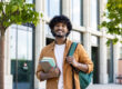 Confident male student at college, holding books and backpack.
